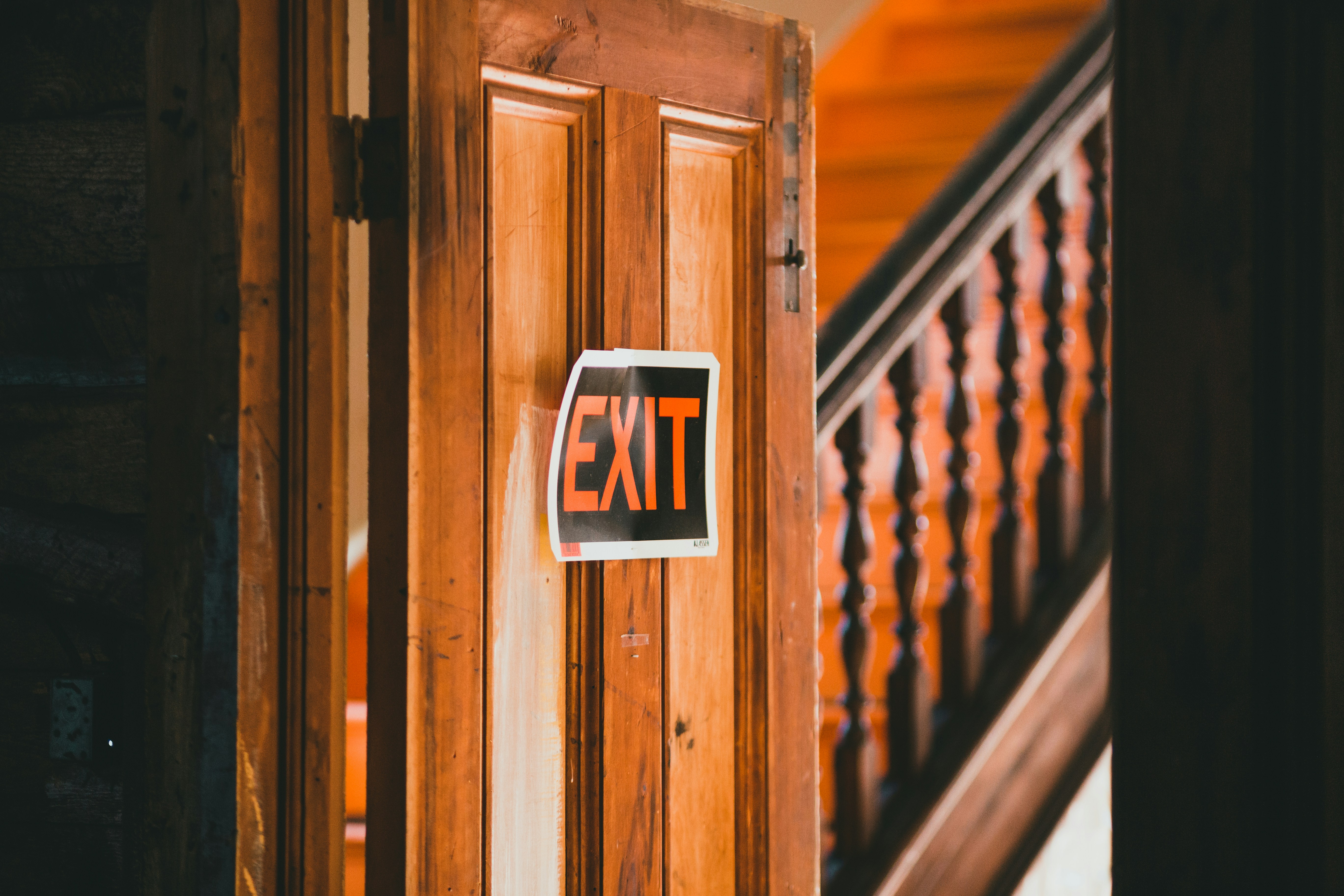 Exit sign on a wooden door, representing volunteers leaving a charity